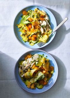 two blue bowls filled with vegetables on top of a white table cloth next to each other