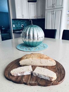 some bread is on a wooden board on the kitchen counter top next to an orange pumpkin