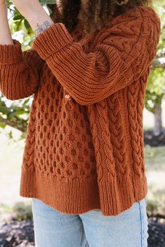 a woman in an orange sweater is holding flowers