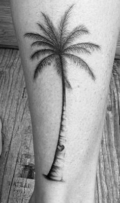 a black and white photo of a palm tree tattoo on the leg, which has a heart in it