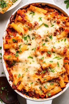 a casserole dish filled with pasta and cheese, topped with fresh parsley