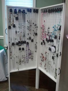 a white room divider with lots of necklaces on it