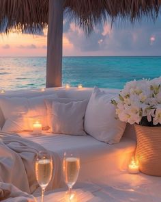 a table with candles and flowers on it next to the ocean