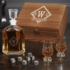 an empty glass next to two glasses and a wooden box with the name wilson on it