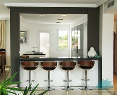 a kitchen with four stools and a bar in front of the counter top area