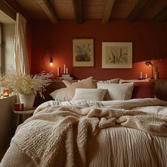 a bedroom with red walls, white bedding and candles on the nightstands in front of the bed