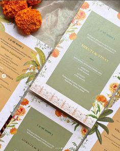 the wedding stationery is laid out on top of each other, with orange flowers