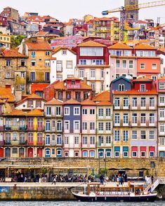 the city is full of colorful buildings and boats on the water in front of it