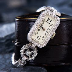 This regal circa 1950s wristwatch features a rectangular case bead set with thirty-six (36) round single cut diamonds. The case measures 24.2mm long by 14.0mm wide and 7.1mm deep. The case houses a manual wind 17 jewel Gublin movement, topped with a white dial and acrylic crystal. The bracelet is bezel set with two (2) round old European cut diamonds and bead set with twenty-six (26) round single cut and twenty-three (23) round transitional brilliant cut diamonds. The case is #11872 and engraved Charlotte Branch on the back. These beautiful old watches are typically for fashion rather than accurate time keeping. EraGem is not able to offer any warranty on watch movements. Formal Rectangular Diamond Watch, Rectangular Diamond Watch With Diamond Hour Markers For Evening, Timeless Rectangular Diamond Watch For Formal Occasions, Timeless Rectangular Diamond Watch For Evening, Timeless Rectangular Jewelry And Watches For Evening, Diamond Rectangular Watch For Anniversary, Diamond Rectangular Watches For Anniversary, Timeless Silver Rectangular Watch Bands, Rectangular Diamond Watch As Gift