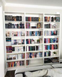 a living room filled with lots of books on top of white shelving unit units