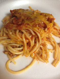 a white plate topped with spaghetti covered in sauce and cheese on top of it's side