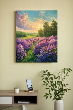 a painting hanging on the wall above a desk with a laptop and potted plant