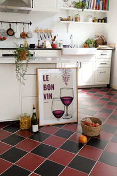 a kitchen with red tile flooring and a wine glass on the counter next to a sign that says le bon vin