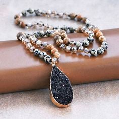 "Approx. 34\" L. Stone pendant approx. size: 1\"x2.2\" Color, pattern may vary. Energize Your Spirit with Black Druzy and Find Joy with Dalmatian Jasper - Embrace the positive energy of this exquisite necklace. Black Druzy, associated with grounding and protection, enhances your spiritual connection and inner strength. Paired with Dalmatian Jasper, known for its joyful and grounding properties, this necklace not only complements your style but also offers a sense of balance and emotional healing. Dive into creativity and find your inner peace with this unique piece of boho chic jewelry. This handcrafted necklace features the captivating beauty of Black Druzy Stone and the playful charm of Dalmatian Jasper. Each natural stone bead is carefully selected and knotted to create a stunning, one- Boho Chic Jewelry, Handcrafted Necklace, Bohemian Chic, Energy Crystals, Unique Necklaces, Stone Pendants, Stone Beads, Boho Jewelry, Natural Stones