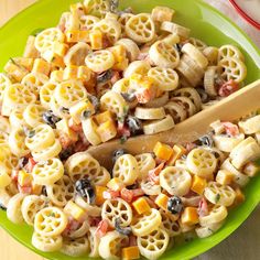 a green bowl filled with pasta salad on top of a table