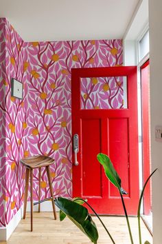 a red door in front of a pink and yellow wallpaper with flowers on it