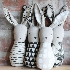 three stuffed rabbits sitting next to each other on a wooden shelf in front of a brick wall