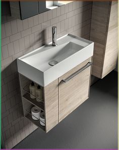 a bathroom sink sitting under a mirror next to a wall mounted faucet and cabinet