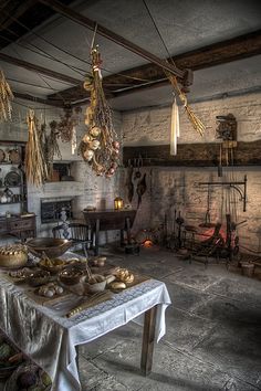 an old fashioned kitchen with lots of food on the table and lights hanging from the ceiling