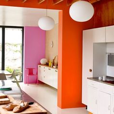 an orange and pink kitchen with white cabinets