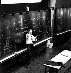 a man standing in front of a blackboard with writing on it