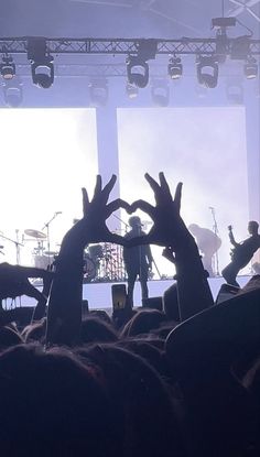 the crowd is holding their hands up in front of stage lights