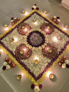 a decorated square with candles and flowers on the floor in front of it is an image of a flower arrangement