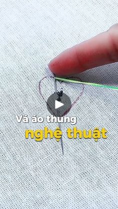 someone is stitching something on the fabric with their thumbnails and using a needle