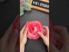 a person holding a pink flower in their hands with the words viki studio on it