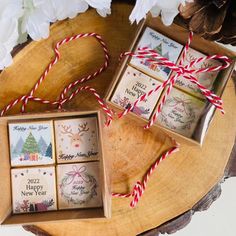 four small christmas cards in a box on a wooden tray with twine red and white ribbons