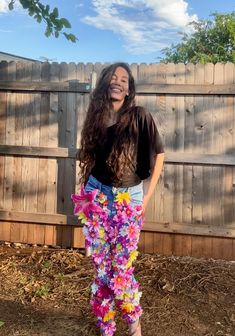 a woman standing in front of a wooden fence with flowers on her leggings