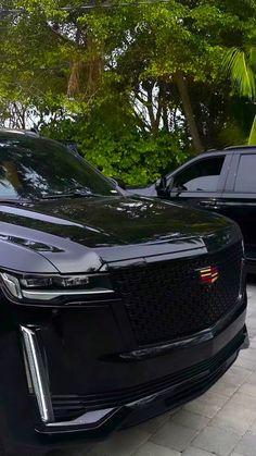 a black car is parked in front of some trees