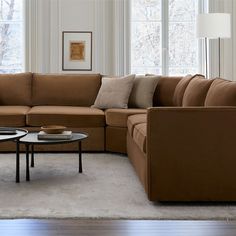 a living room filled with lots of furniture next to two windows and a rug on the floor