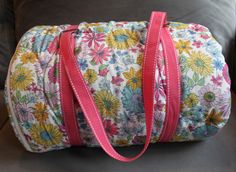 a flowered bag sitting on top of a couch with a pink ribbon around it