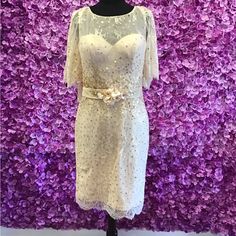 a white dress on a mannequin stand in front of a purple flower wall