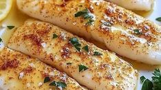 three fish fillets on a plate with lemons and parsley sprinkled