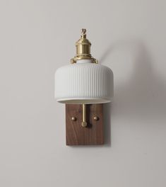 a wall light with a white shade hanging from it's side on the wall