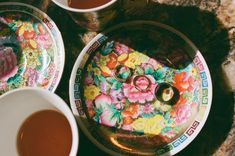 there are two plates with flowers on them and cups next to each other in front of the plate