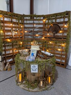 a table with candles and decorations on it in front of a wooden fence that is decorated with moss