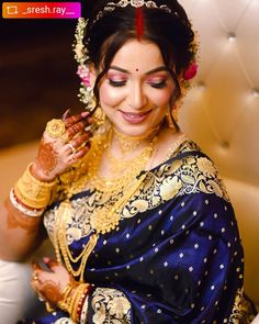 a woman in a blue and gold sari smiles while holding her hands up to her face