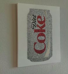 a coca cola can with the word coke on it is hanging on a wall in a room