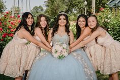 a group of young women standing next to each other in front of bushes and flowers