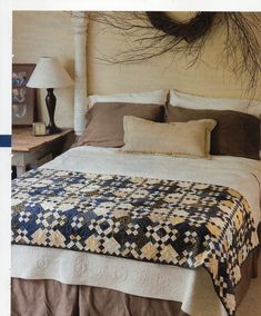 a bed with a quilt on it in a bedroom next to a night stand and lamp