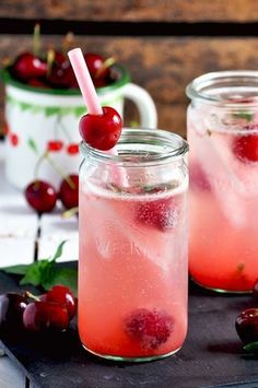 two mason jars filled with liquid and cherries