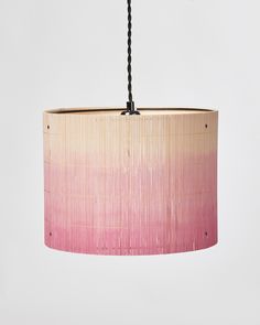 a pink and white lamp hanging from a light fixture with black beads on the end