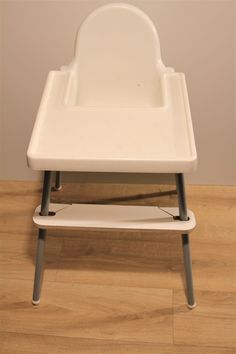 a white high chair sitting on top of a hard wood floor