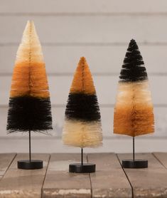 three small trees with different colors and sizes on top of each other in black, orange, and white