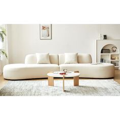 a large white couch sitting on top of a wooden floor next to a coffee table