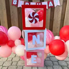 a birthday decoration with balloons and candies on the ground in front of a wooden fence