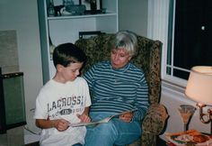 an older woman sitting next to a young boy on a chair in a living room